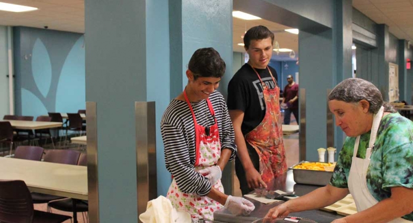 Young people prepare food during a service project with outward bound.